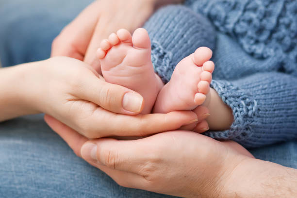 Baby feet in parents hands. Tiny Newborn Baby's feet on parents shaped hands closeup. Parents and they Child. Happy Family concept. stock photo