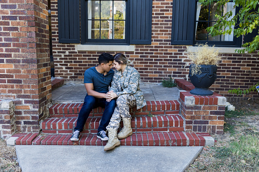 The mid adult military couple sits on their front stoop to pray before her deployment.