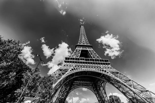 World famous Eiffel tower under a blue sky with clouds in black and white