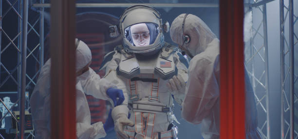 Medium shot of scientists helping a male astronaut to put on gloves