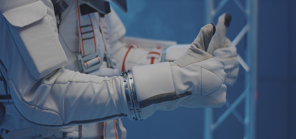 Close-up of scientists helping an astronaut to put on gloves