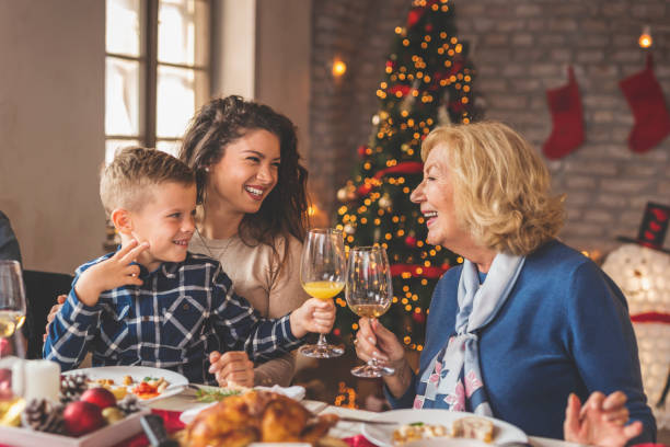 familia celebrando la navidad durante la cena - los niños y los padres brindis bebidas mientras almuerza fotografías e imágenes de stock