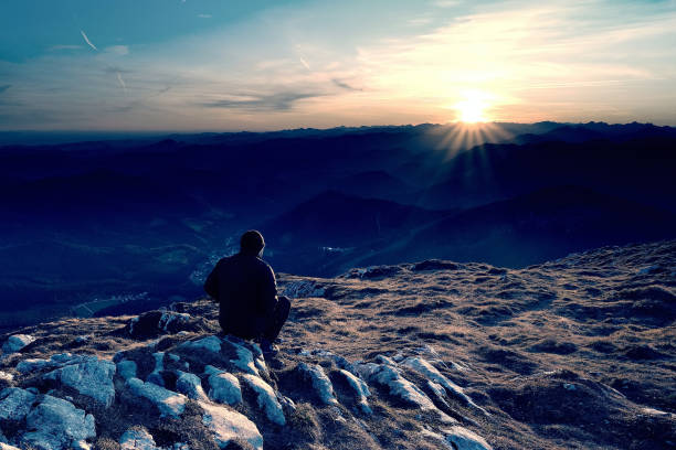 istock Backpacker sit on cliff edge and looks at long mount valley 1189168259