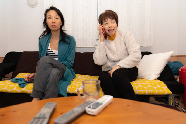 mère et descendant regardant la tv - japan serious family senior adult photos et images de collection