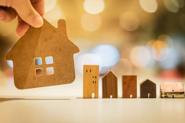 istock Hand choosing mini wood house model from model on wood table, selective focus, Planning to buy property. Choose what's the best. A symbol for construction ,ecology, loan concepts 1189173347