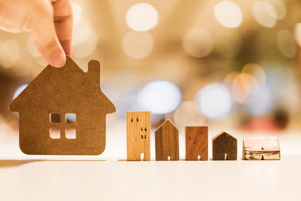 istock Hand choosing mini wood house model from model on wood table, selective focus, Planning to buy property. Choose what's the best. A symbol for construction ,ecology, loan concepts 1189173731