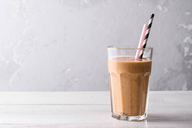 batido de proteína de chocolate sobre un fondo de madera blanca. batido fresco con arándano sobre una mesa ligera. un vaso de batido de chocolate. - vitality food food and drink berry fruit fotografías e imágenes de stock