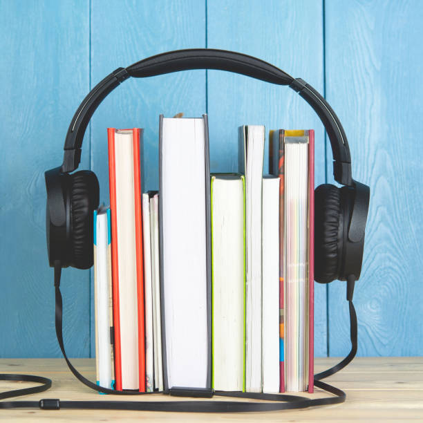 istock headphone and books on blue background.audio book 1189176785