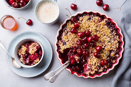 Cherry, red berry crumble in baking dish. Grey stone background. Close up. Top view.