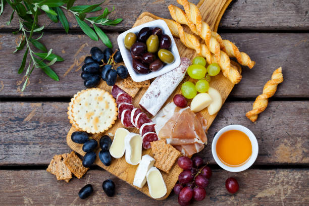 aperitivos de queso y carne en tabla de cortar sobre fondo de madera. vista superior. - cheese antipasto cracker grape fotografías e imágenes de stock