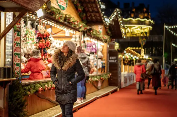 A woman, wrapped up for the weather, looking at Christmas stalls in Edinburgh, Scotland.