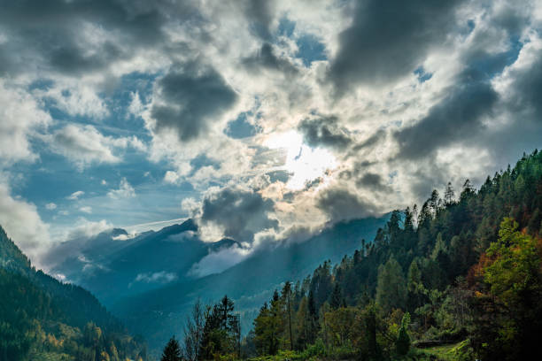 the sun breaking through the clouds over the cordevole valley on a sunny autumn day - cordevole valley imagens e fotografias de stock