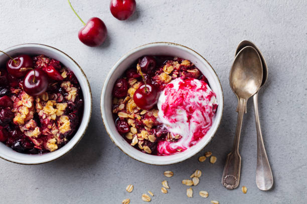 istock Cherry, red berry crumble with ice cream in bowls. Grey stone background. Top view. 1189180814
