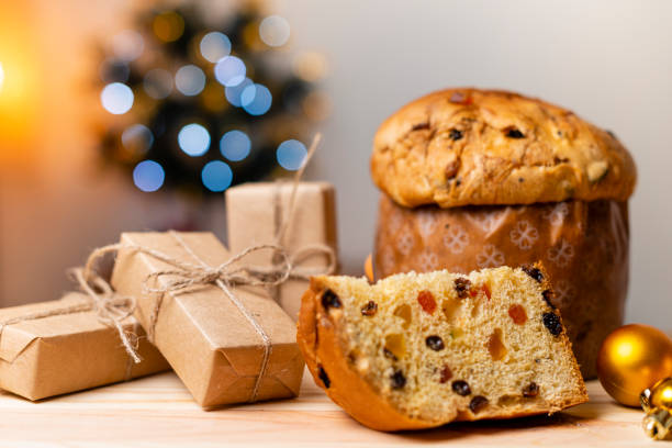 köstliche panettone scheibe mit kandierten früchten mit blinkenden verschwommenen weihnachtsbeleuchtung. trockene früchte. geschenke mit weihnachtsschmuck - bakery food defocused table stock-fotos und bilder