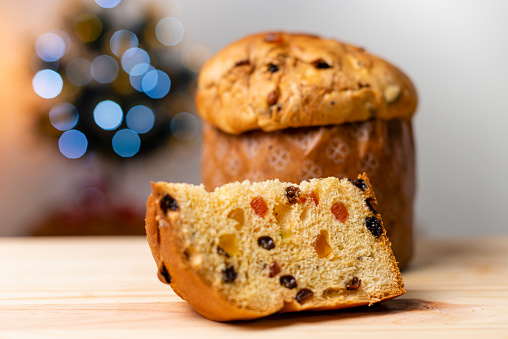 Delicious Panettone slice with candied fruits with blinking blurred christmas lights. Dry fruits.