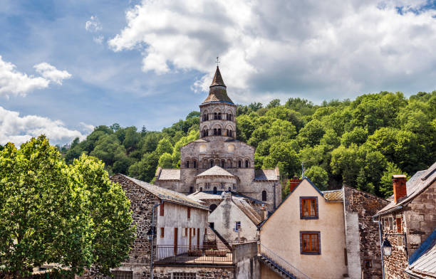 Basilica Notre Dame of Orcival seen from the village. Parts of old houses are at foreground. Puy-de-Dome department in French Auvergne. Basilica Notre Dame of Orcival seen from the village. Parts of old houses are at foreground. Puy-de-Dome department in French Auvergne. orcival stock pictures, royalty-free photos & images