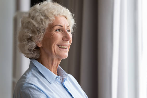 istock Happy elderly woman looking through window dreaming thinking feeling hope 1189188490