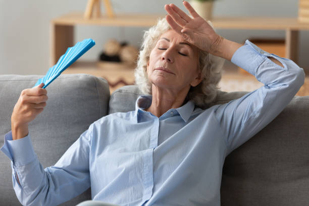 Tired senior woman waving fan feel hot sit on sofa Tired annoyed senior woman holding waving fan feel hot sit on sofa at home without air conditioner, overheated exhausted old elder grandma sweating suffer from hormone problem summer heat concept hand fan photos stock pictures, royalty-free photos & images