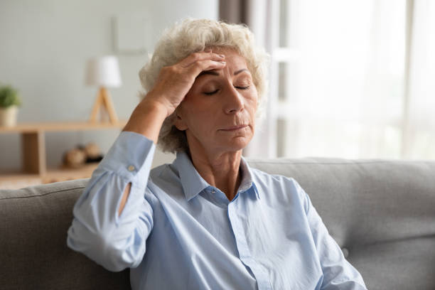 istock Upset senior lady feeling dizzy having headache sit on sofa 1189188500