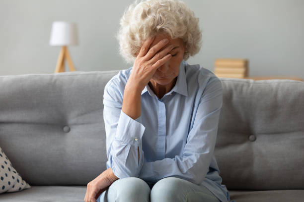 istock Depressed old woman sit on sofa suffering from headache grief 1189188502