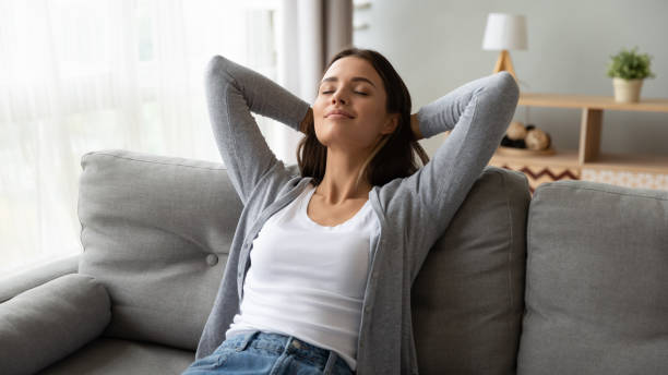 relaxed serene young woman lounge on comfortable sofa at home - adult beautiful caucasian equipment imagens e fotografias de stock