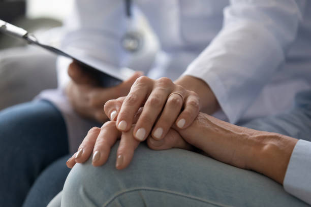 giovane donna medico tenendo la mano della paziente nonna anziana, primo piano - patient doctor male talking foto e immagini stock