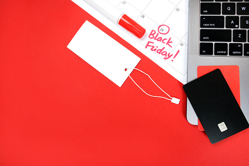 Flat lay with credit cards, price tag, laptop, calendar and highlighter pen isolated on red. Black friday concept.