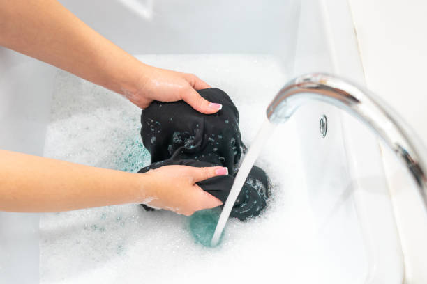 istock Female hands washing black clothes in basin 1189191827