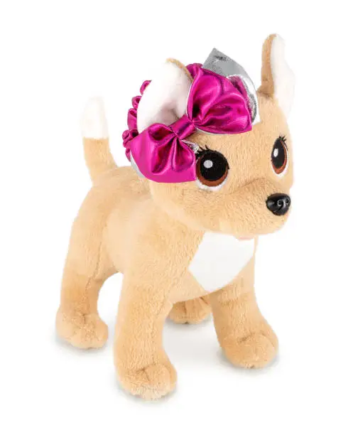 Cute dog doll with pink ribbon isolated on white background with shadow. Playful bright brown dog sitting on white underlay. Puppy plush stuffed puppet toy for children. Plaything for kids.