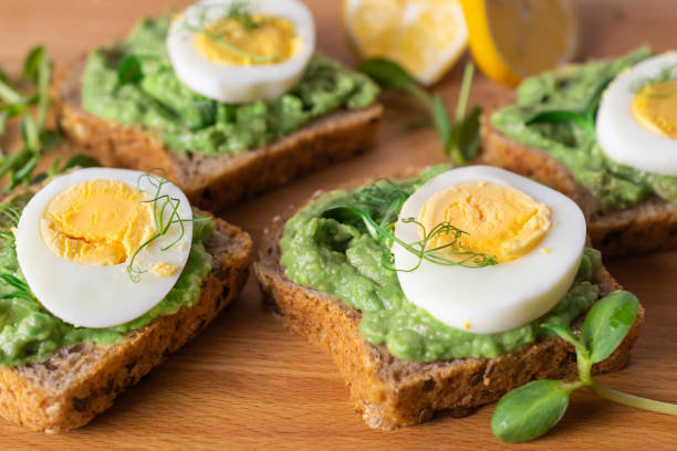 istock Healthy toasts with whole grain bread, avocado and boiled egg on wooden board. 1189194806