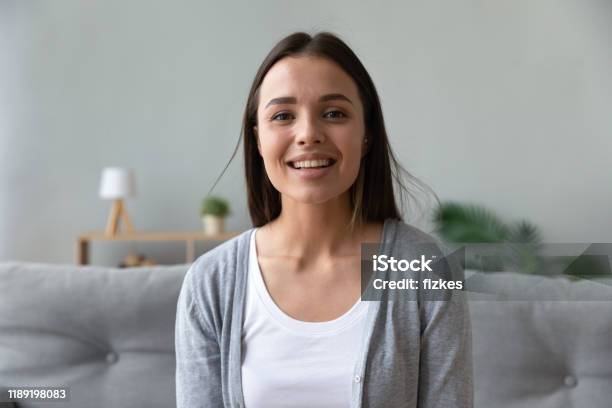Uśmiechnięta Atrakcyjna Młoda Dama Patrząca Rozmawiając Z Kamerą W Domu - zdjęcia stockowe i więcej obrazów Kobiety