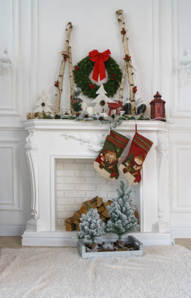 istock Decorated white fireplace for Christmas with small Christmas trees and red socks pair 1189202586