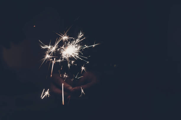 istock hand holding a burning sparkler firework bengal light. space for text. burning sparks closeup in female hand in dark. happy new year and merry christmas concept. happy holidays, toned 1189205135