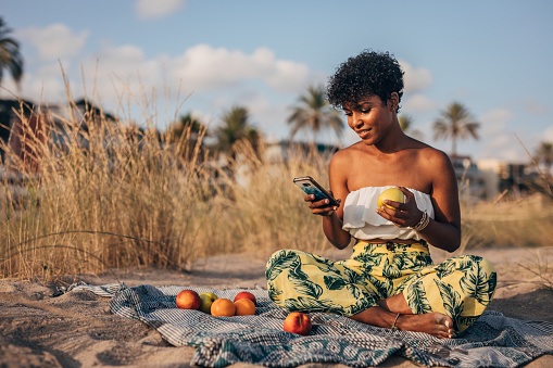 Woman using phone while  sitting and relaxing at the beach