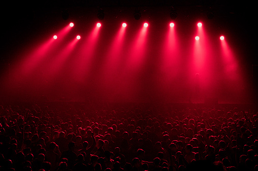 red concert light equipment and crowd of unrecognized people at big music concert in nightclub