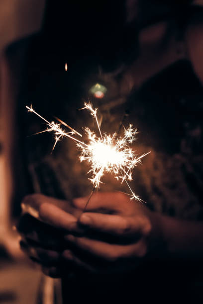 istock hand holding a burning sparkler firework bengal light. space for text. burning sparkler closeup in female hand in dark. happy new year and merry christmas concept. happy holidays 1189206215