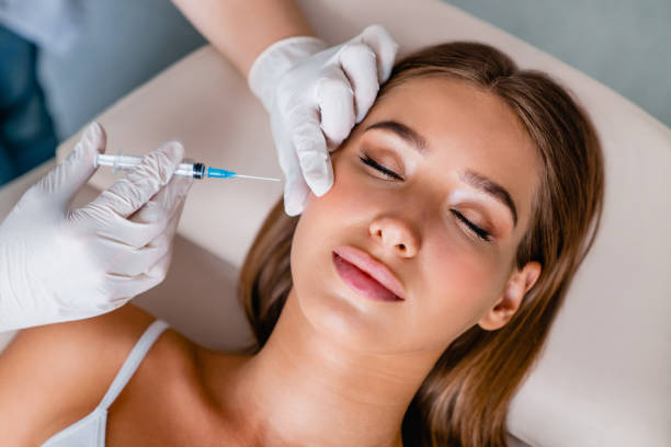 giovane donna ottiene iniezioni facciali di bellezza in salone - plastic beauty injecting protective glove foto e immagini stock