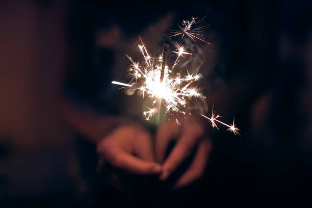 istock hand holding a burning sparkler firework bengal light. space for text. burning sparkler closeup in female hand in dark. happy new year and merry christmas concept. happy holidays 1189207686