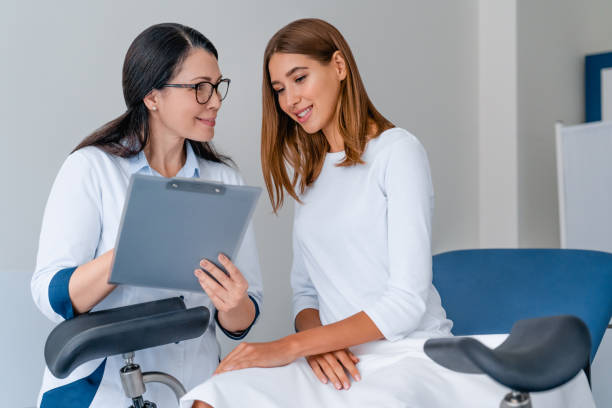 erwachsene lächelnde gynäkologin arbeitet mit patientin in moderner klinik - gynecological examination stock-fotos und bilder