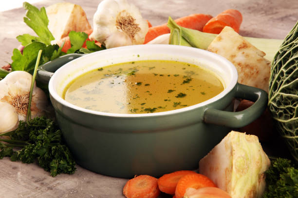 istock Broth with carrots, onions various fresh vegetables in a pot - colorful fresh clear spring soup. Rural kitchen scenery vegetarian bouillon stock 1189214022