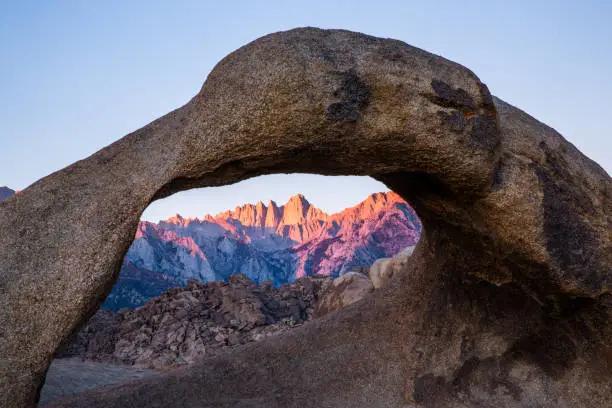 First light of the sunrise on Mount Whitney looking through Mobius Arch in the Alabama Hills on the way to Whitney Portal.