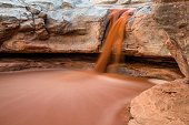 Flash flood muddy red water spilling over cliff in southern Utah.