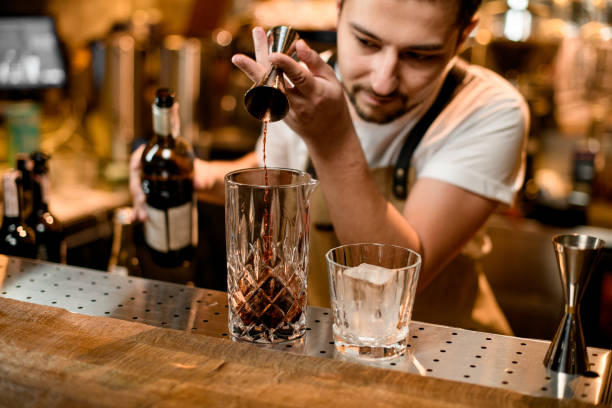 istock Bartender pouring alcohol from jigger to glass 1189225068