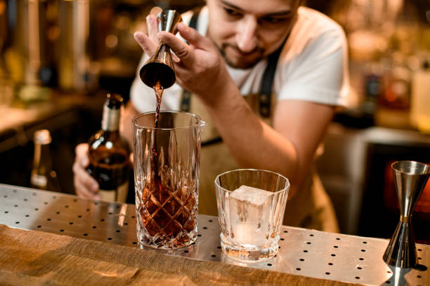 バーテンダーはジガーからガラスにアルコールを注ぎます - whisky alcohol pouring glass ストックフォトと画像