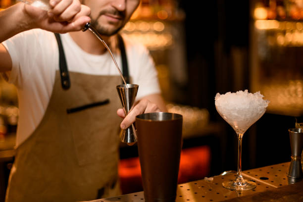 istock Bartender pours cocktail with bar spoon and jigger 1189225817