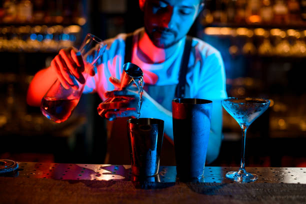istock Bartender pours cocktail with jigger in neon lights 1189225846
