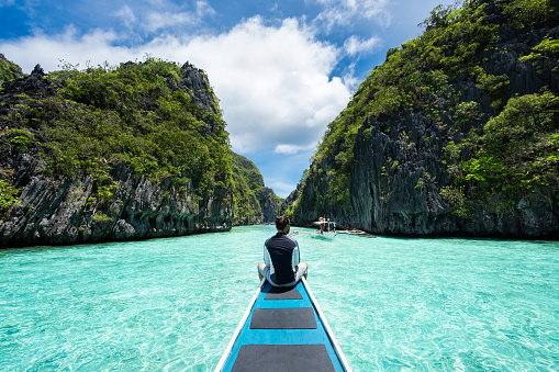 El Nido, Palawan, Philippines, traveler sitting on boat exploring the natural sights around El Nido on a sunny day.