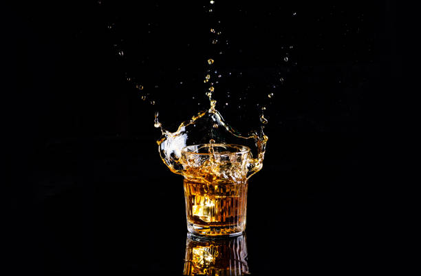 whiskey with splash on black background, brandy in a glass