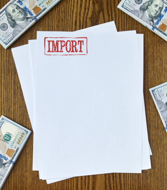Imports Looking down on wooden desk with blank paper with “import” stamp 100 dollar bills one hundred dollar stamp stock pictures, royalty-free photos & images