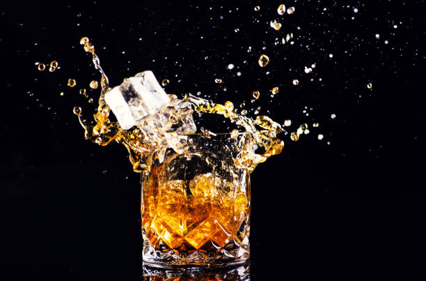 istock whiskey with splash on black background, brandy in a glass 1189230040